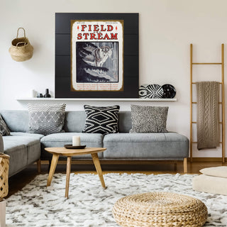 Field & Stream Cover May 1907 - Wood & Metal Wall Art (Copy) displayed above a modern gray sofa with patterned pillows.