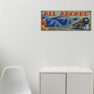 Vintage-style train poster with 'All Aboard' text on a white wall above a white cabinet.