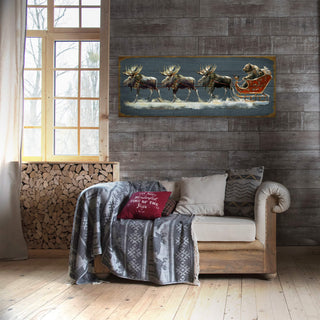 Cozy living room with wooden walls, a sofa, and a painting of moose and a reindeer sleigh.